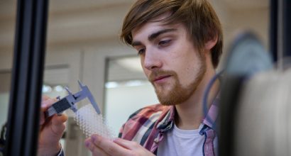 Mies mittaa työntömitalla 3D-tulostettua osaa.