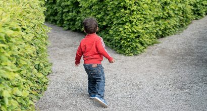 Pieni lapsi valitsemassa polkua puutarhassa.